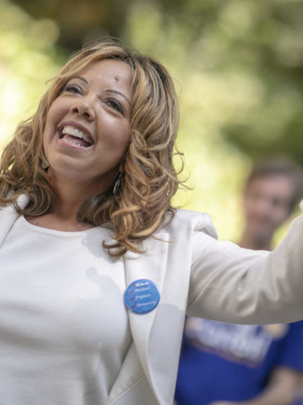 Lucy McBath smiles while pointing her finger in the air at a canvassing event