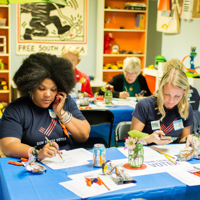 Two volunteers wearing Gun Sense Voter shirts make calls at a phonebanking event