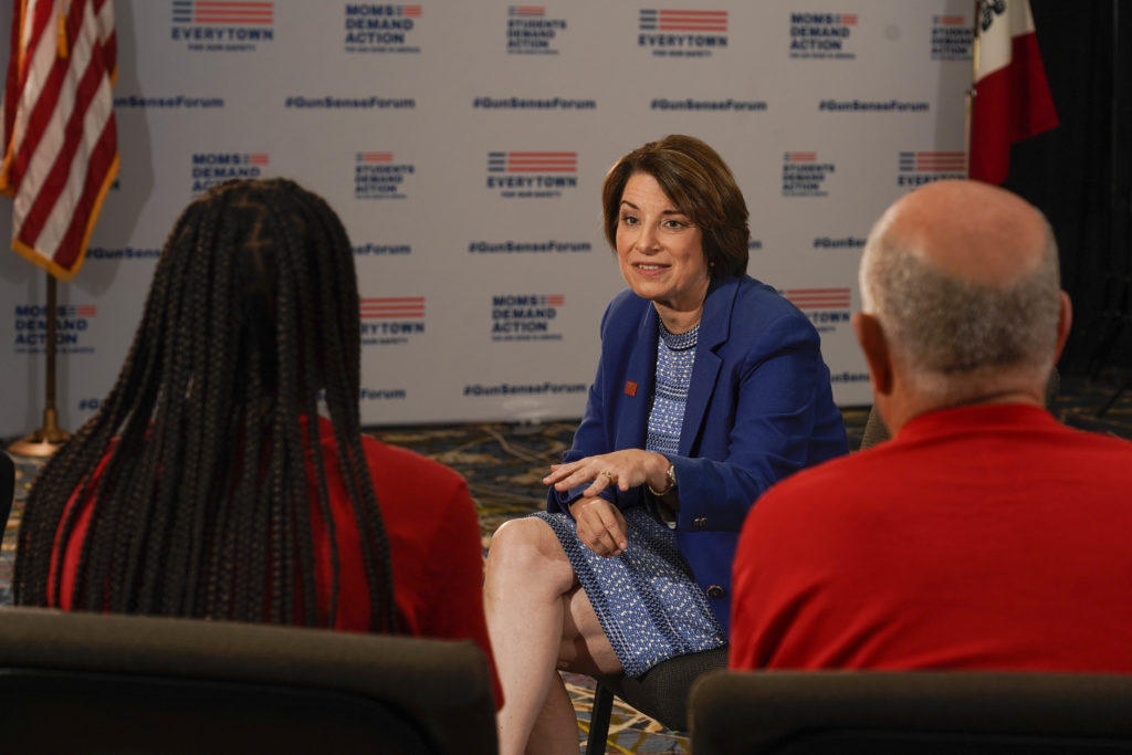 Amy Klobuchar sits and speaks with a group of volunteers at the Gun Sense Forum. 
