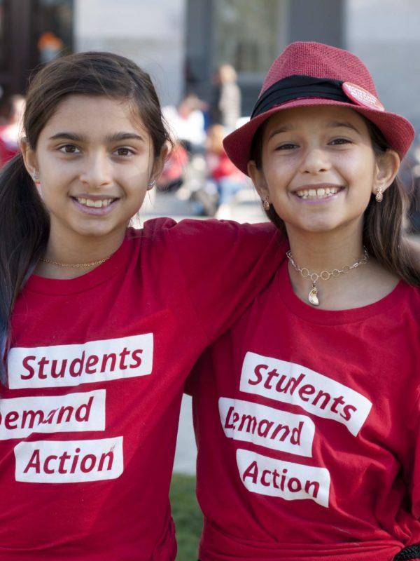 Two young girls smile while wearing Students Demand Action t-shirts