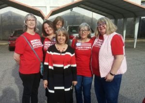 Gov. Lujan Grisham stands and poses for a photo with a group of four Moms Demand Action volunteers