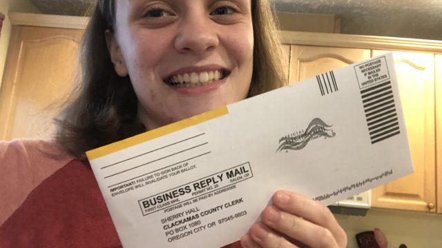 A volunteer holds up a mail in ballot