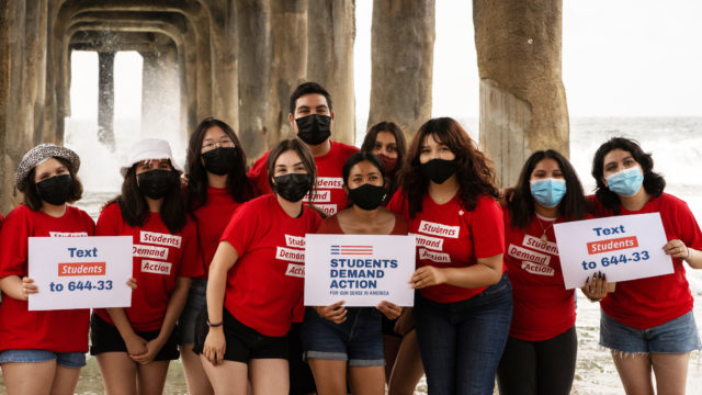 A group of 10 Students Demand Action volunteers pose for a photo on a beach