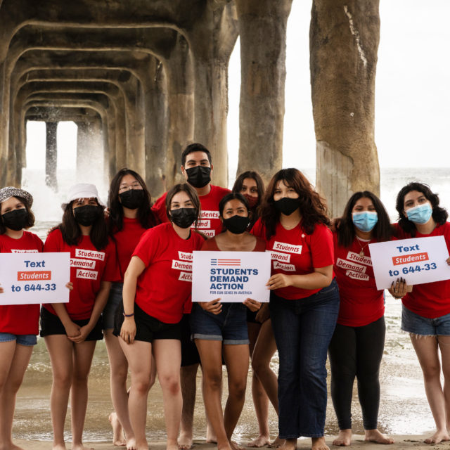 A group of 10 Students Demand Action volunteers pose for a photo on a beach