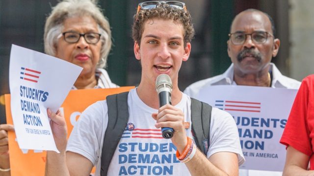 Mitchell speaks at an event while wearing a Students Demand Action t-shirt