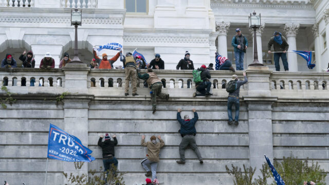 Supporters of President Donald Trump climb the west wall of the the U.S. Capitol