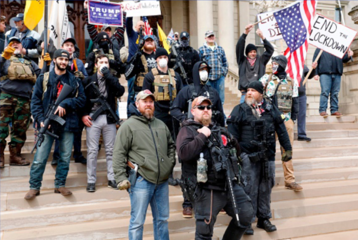 Armed protestors stand in a group on the steps of a building