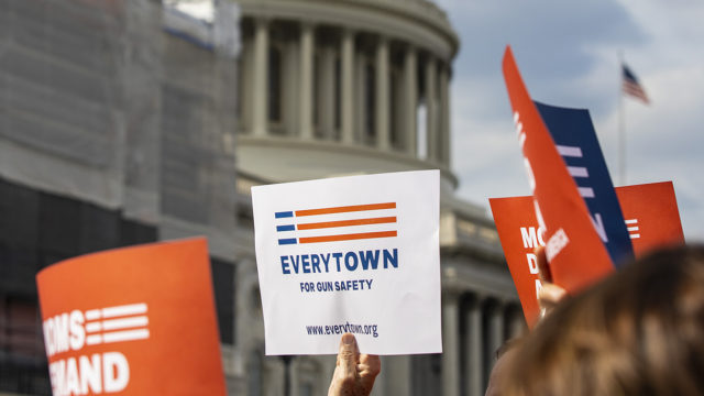 An Everytown sign is raised in a crowd in front of the Capitol