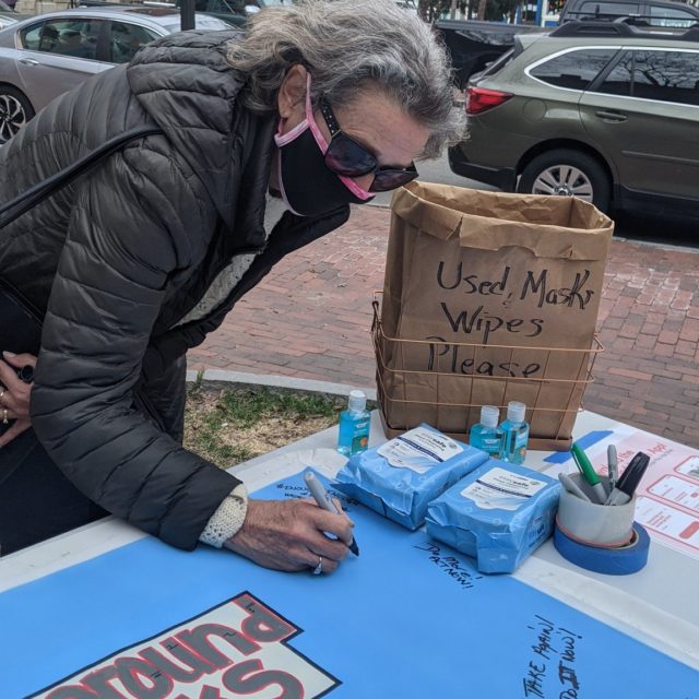 A woman signs the Background Checks Now banner at a stop in Portland, ME on the Road Trip for Background Checks