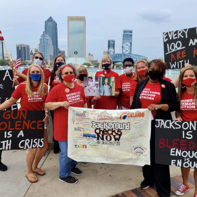 A group of Moms Demand Action volunteers in Jacksonville, FL pose with Background Checks Now signs on a stop in Jacksonville, FL during the Road Trip for Background Checks