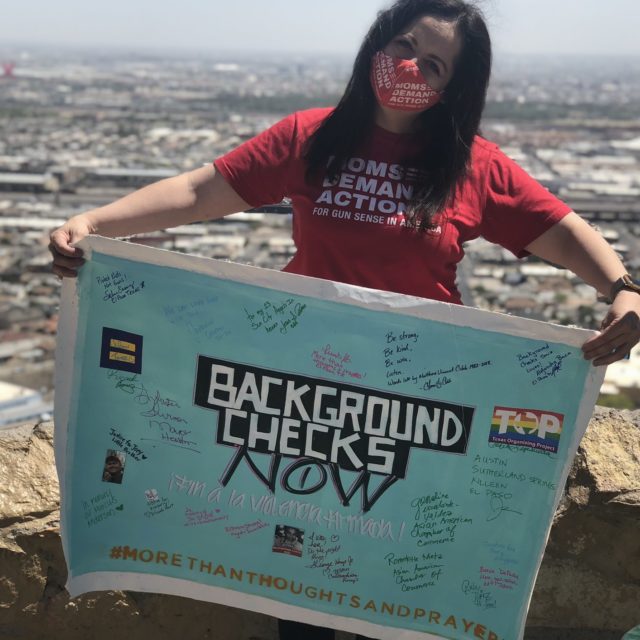 A volunteer in Texas holds up a Background Checks Now on the Road Trip for Background Checks