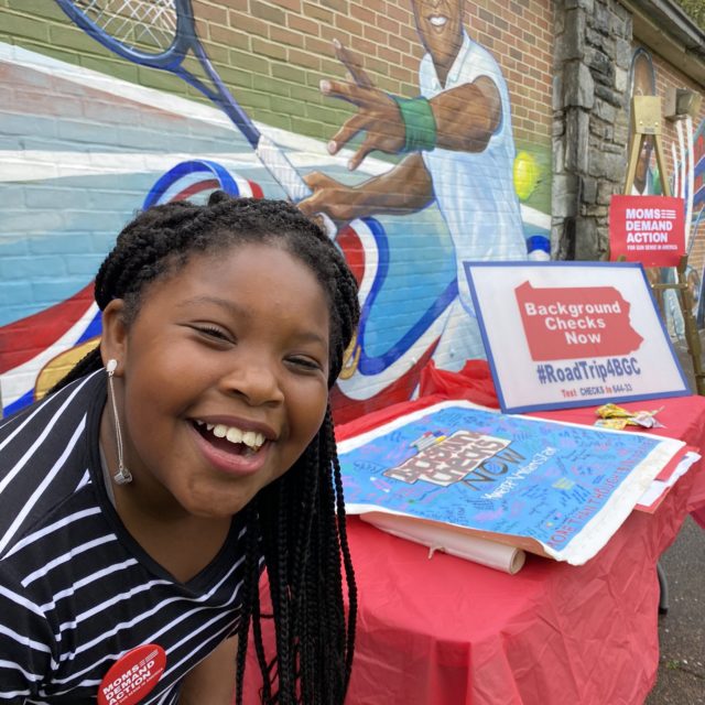 A volunteer in Philadelphia smiles with the mural in the background