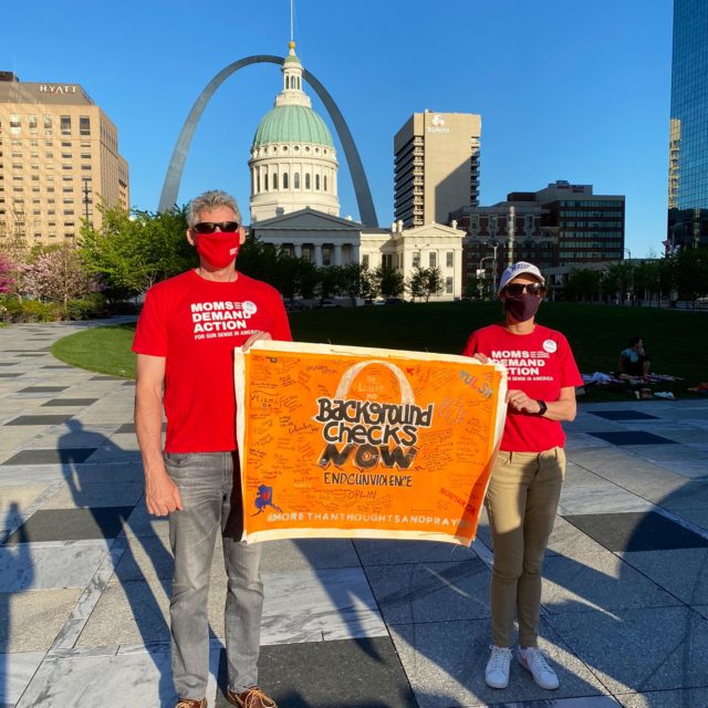 Volunteers hold up a background checks now sign at the St Louis stop on the Road Trip for Background Checks
