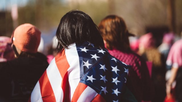 A person with an American flag draped over their shoulders at a march