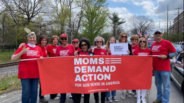 Kentucky Moms Demand Action volunteers pose for a photo wearing their red Moms Demand Action t-shirts and carrying a red Moms Demand Action banner