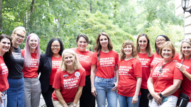 Moms Demand Action volunteers pose in red Moms Demand Action t-shirts alongside founder Shannon Watts