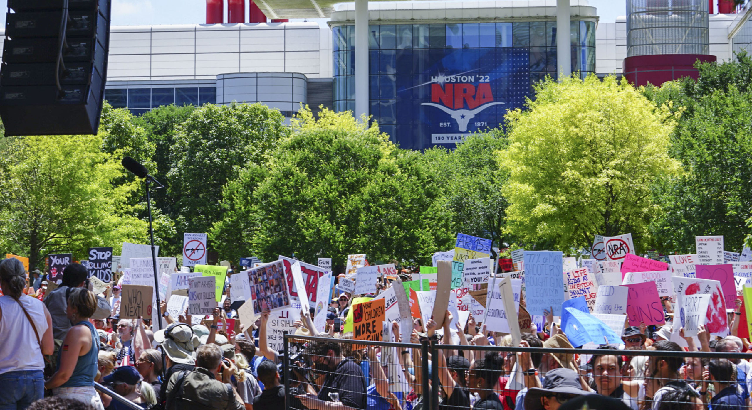 Protesters hold up signs outside the NRA Convention