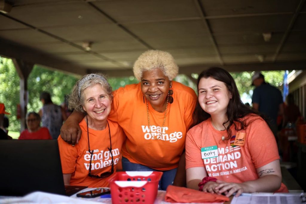 People pose for a photo at a table wearing Wear Orange t-shirts