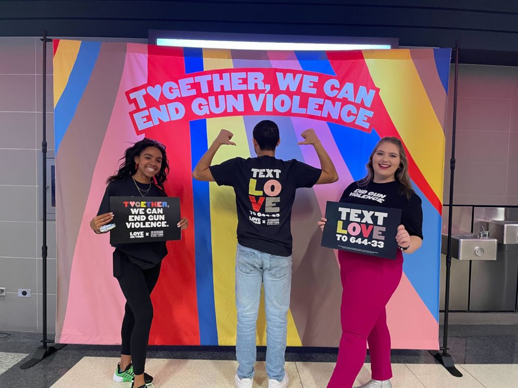 Volunteers pose with Love on Tour x Everytown signs