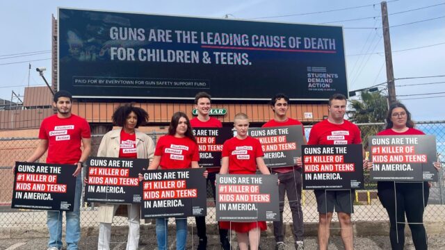 Students Demand Action volunteers holding up signs that say “Guns are the #1 killer of kids and teens in America.”