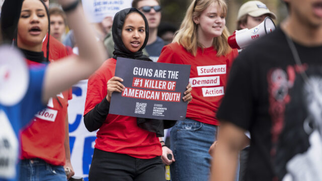 A Students Demand Action volunteer holds a sign that says “Guns are the #1 killer of American youth”