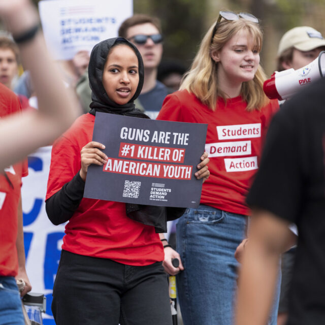 A Students Demand Action volunteer holds a sign that says “Guns are the #1 killer of American youth”