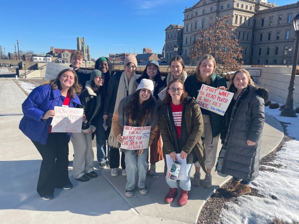 Michigan Students Demand Action volunteers pose for a photo holding signs