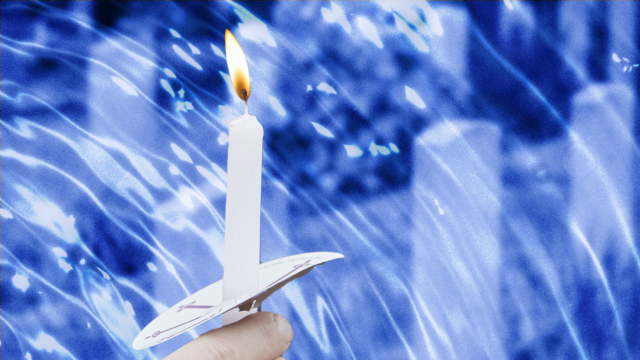 A hand holding a candle with tombstones in the background