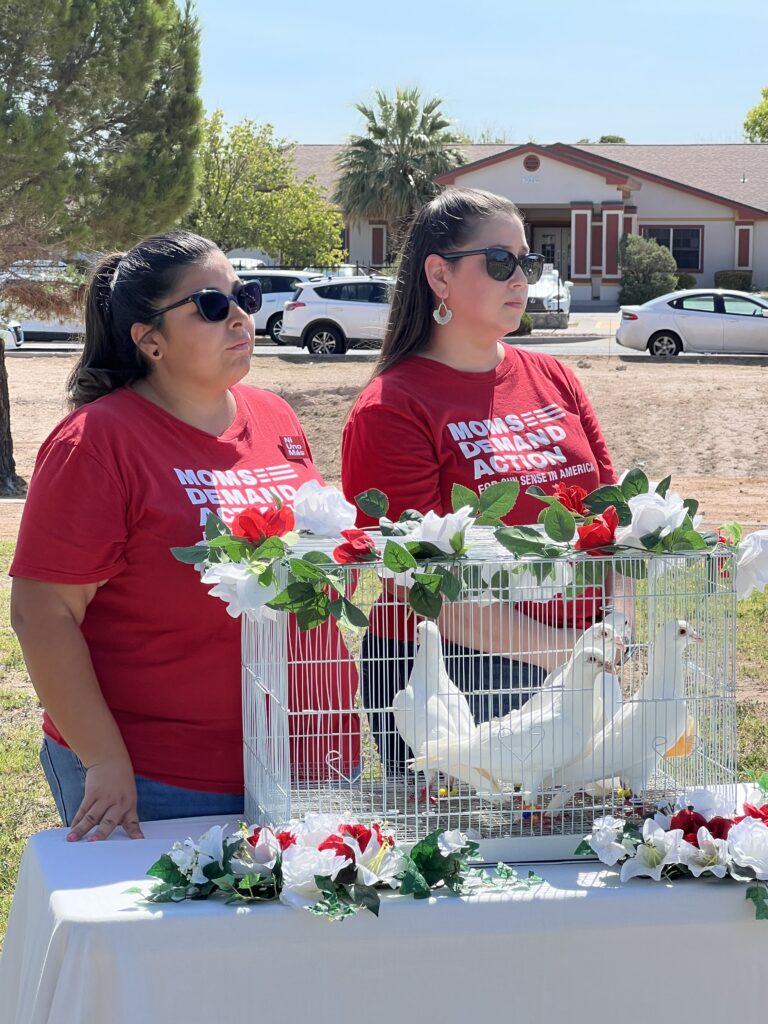 Two Moms Demand Action volunteers stand near an El Paso memorial