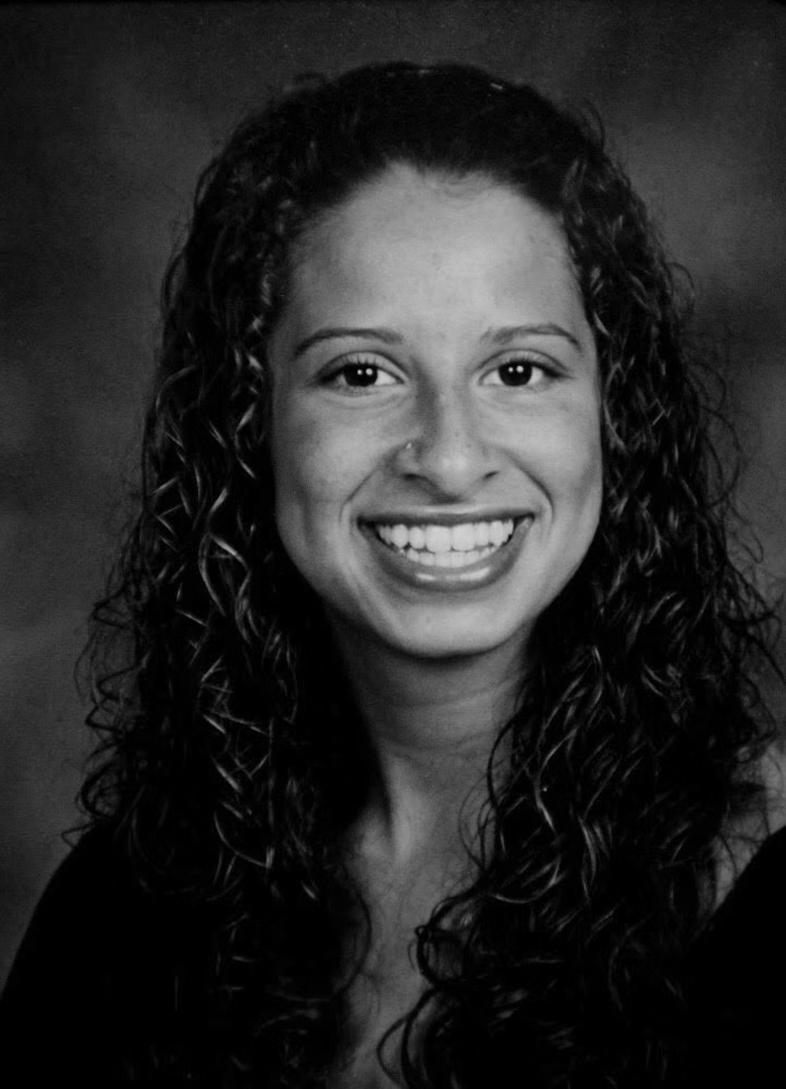 An image of Darien Richardson, a 25-year-old woman. She is smiling at the camera and has long, curly hair.