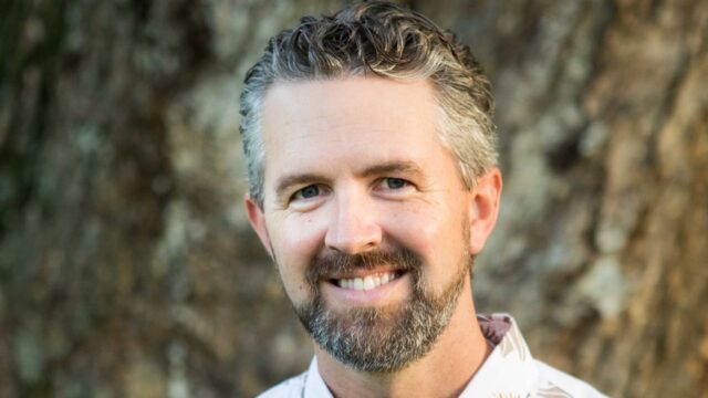 Capt. Chris Marvin is a retired member of the U.S. Army. He is a white male with short grey-and-brown hair, a beard and mustache, and is wearing a white collared shirt.