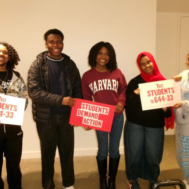 Five students pose for a photo during the Young Changemakers Summit. They hold Students Demand Action signs that say 
