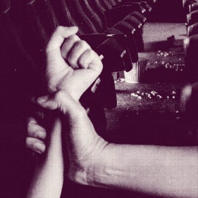 A magenta-hued textured graphic in which a person's hand grips another's wrist in a row of movie theater seats with a bucket of popcorn spilled in the background. The image represents one person's experience with teen dating violence.