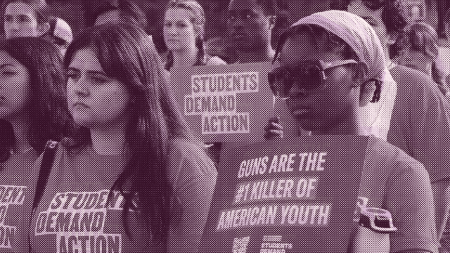A magenta-tinged image of Students Demand Action volunteers at a rally. The students look serious and are wearing Students Demand Action t-shirts. One student holds a sign that reads 