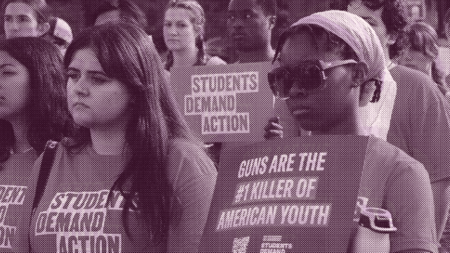 A magenta-tinged image of Students Demand Action volunteers at a rally. The students look serious and are wearing Students Demand Action t-shirts. One student holds a sign that reads 